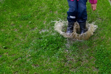 Child jumping into a pool of water on a lawn.